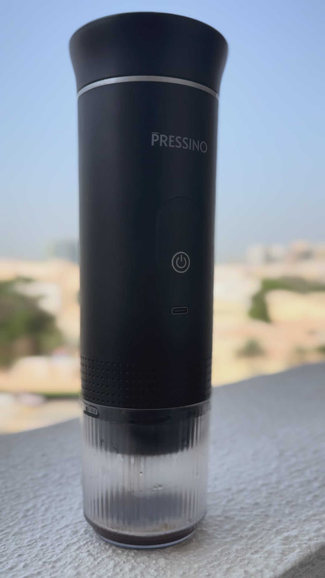 A cinematic close-up of the Pressino One portable espresso maker brewing espresso, showing the metallic nozzle, steam, and rich crema forming in the transparent cup, highlighting the craftsmanship, precision, and sensory detail of the brewing process.